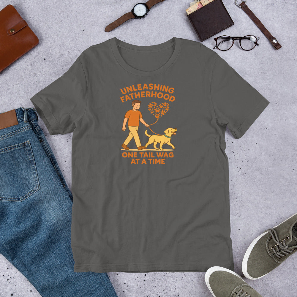 "Unleashing Fatherhood " – Fun Labrador T-Shirt Gray t-shirt with a graphic and text 'Unleashing Fatherhood One Tail Wag At A Time' on a concrete surface with jeans, shoes, and accessories.