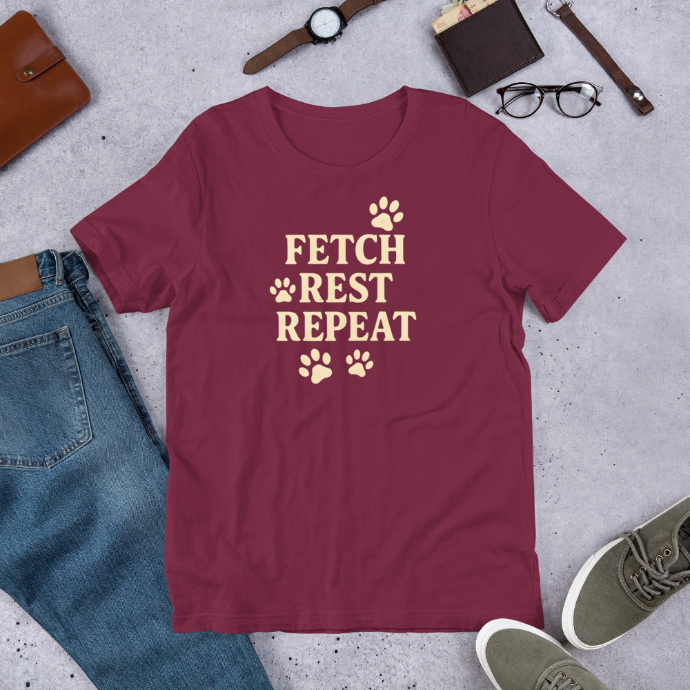 "Fetch Rest Repeat" - Fun Labrador T-Shirt Maroon t-shirt with 'Fetch Rest Repeat' text on a concrete surface with casual items.