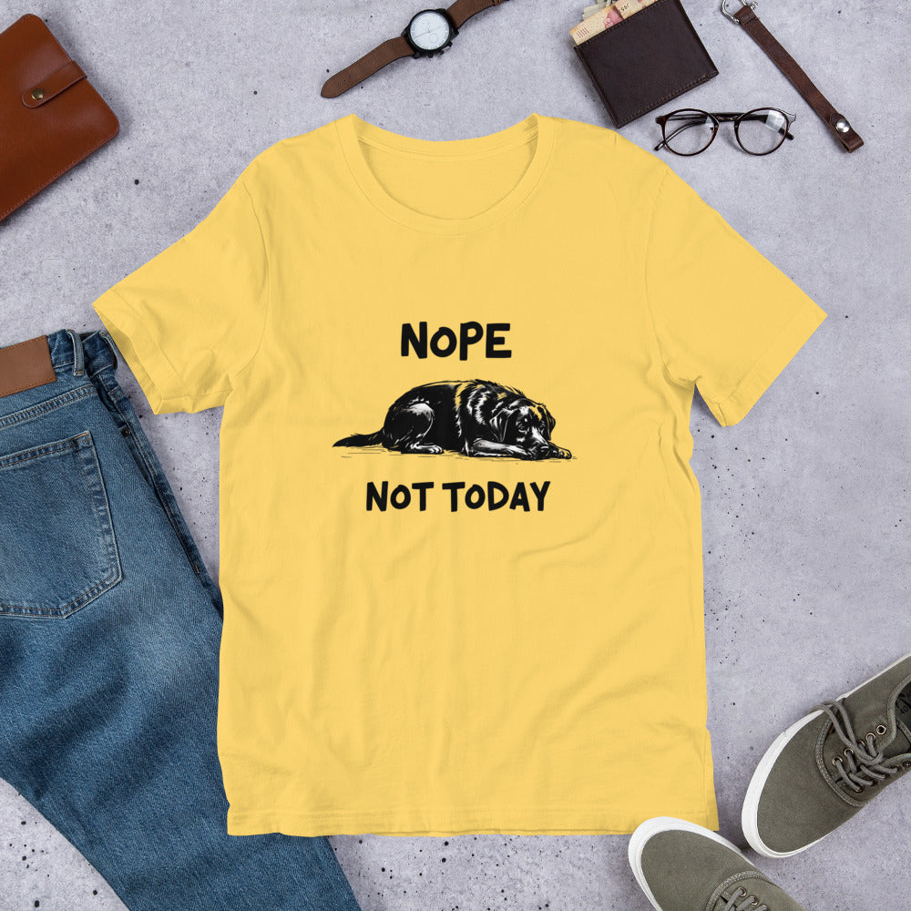 Yellow t-shirt with an illustration of a sleeping black Labrador and the text “Nope Not Today.” Laid out flat with sneakers and accessories. A fun gift for Labrador owners and dog parent apparel fans.
