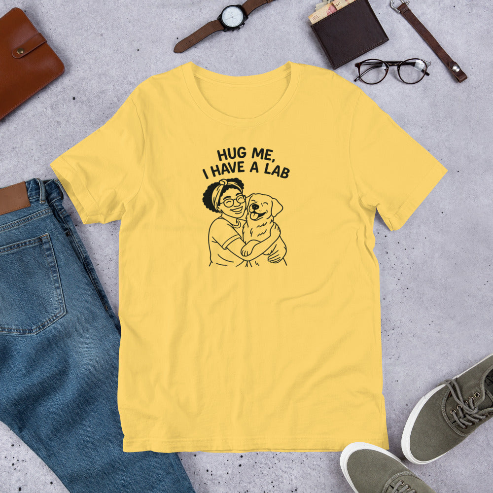 " Hug Me I Have A Lab" - Fun Labrador T-Shirt Yellow t-shirt with 'Hug Me, I Have a Lab' graphic on a concrete surface with jeans and shoes.