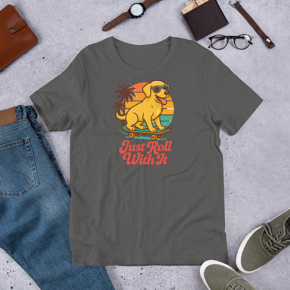 "Just Roll With It "  - Yellow Lab – Fun Labrador T-Shirt Gray t-shirt with a colorful dog graphic and 'Just Roll With It' text, surrounded by jeans, shoes, and accessories on a concrete surface.