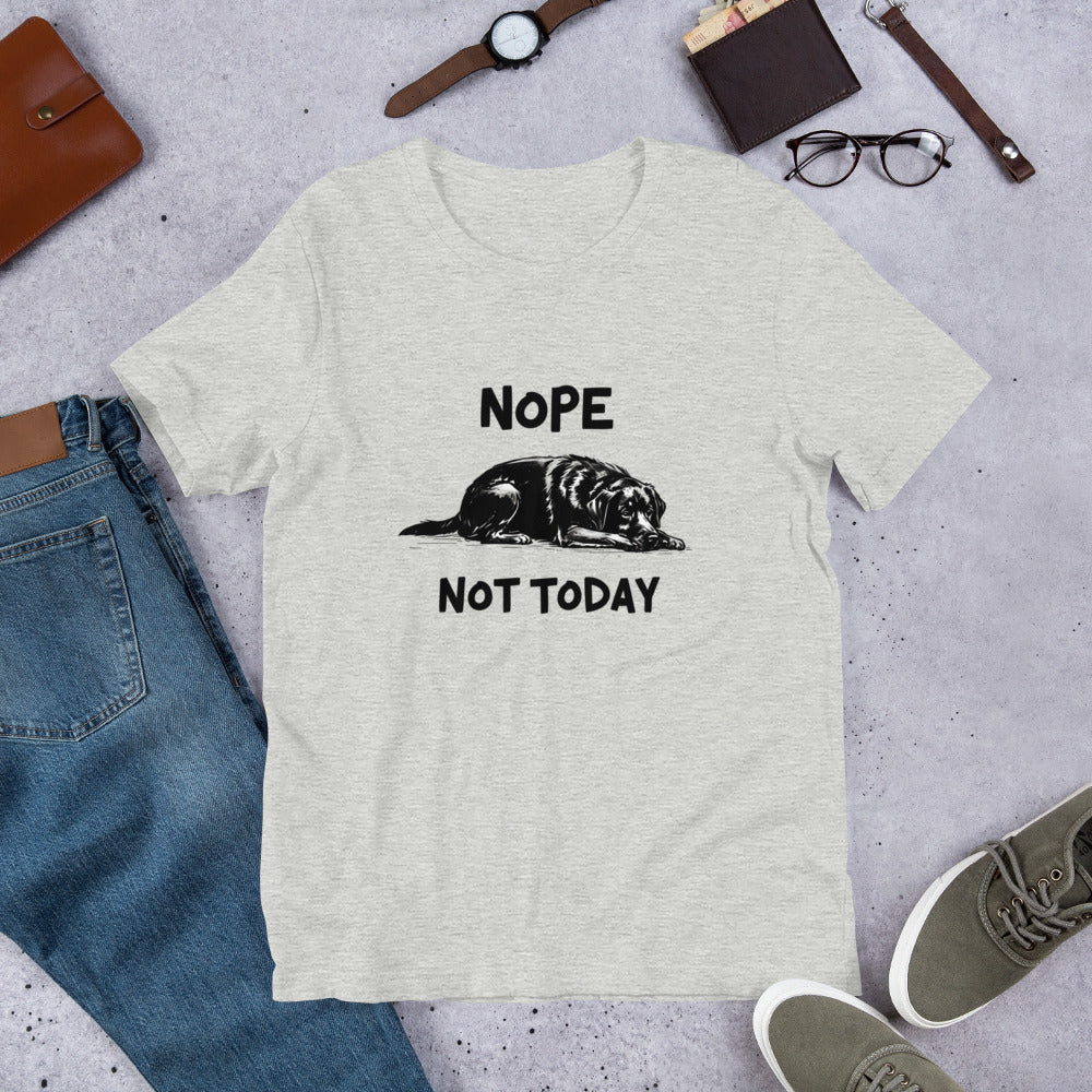 Yellow t-shirt with an illustration of a sleeping black Labrador and the text “Nope Not Today.” Laid out flat with sneakers and accessories. A fun gift for Labrador owners and dog parent apparel fans.