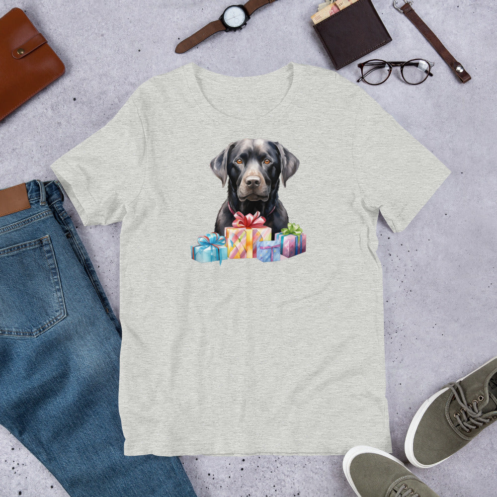 "Black Lab With Presents " – Fun Labrador T-Shirt T-shirt with a dog holding presents graphic on a gray surface with jeans, shoes, and accessories.