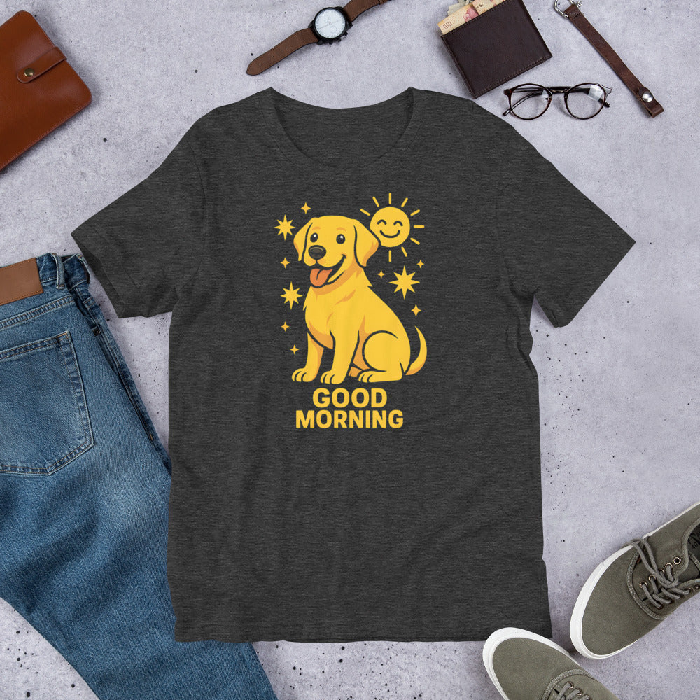 "Good Morning " – Fun Labrador T-Shirt Dark gray t-shirt with a yellow dog graphic and 'Good Morning' text on a concrete surface with jeans, shoes, and accessories.