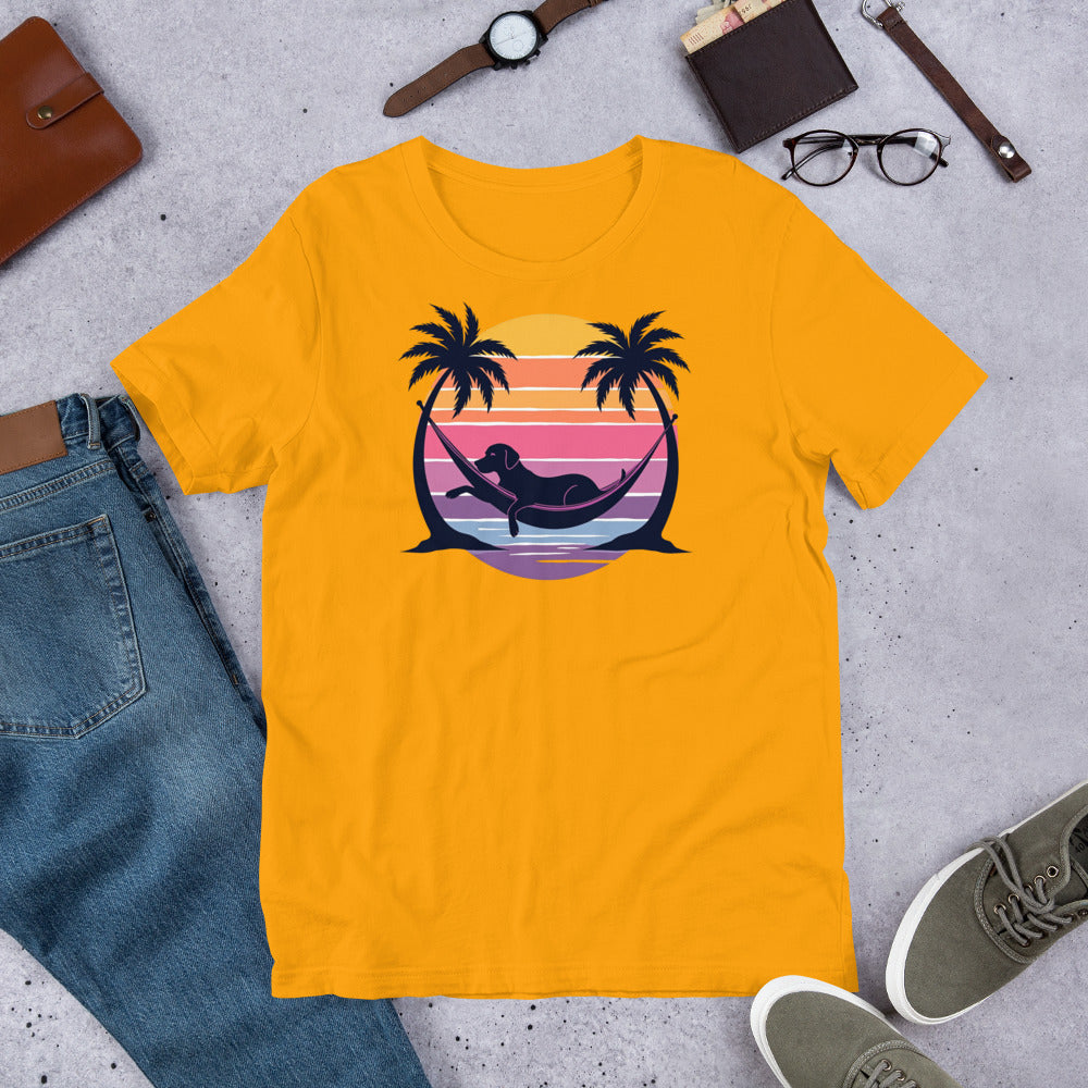 "Labrador In Paradise " – Fun Labrador T-Shirt Yellow t-shirt with a graphic of a mermaid in a hammock between palm trees and a sunset, placed on a concrete surface with jeans, shoes, and accessories.