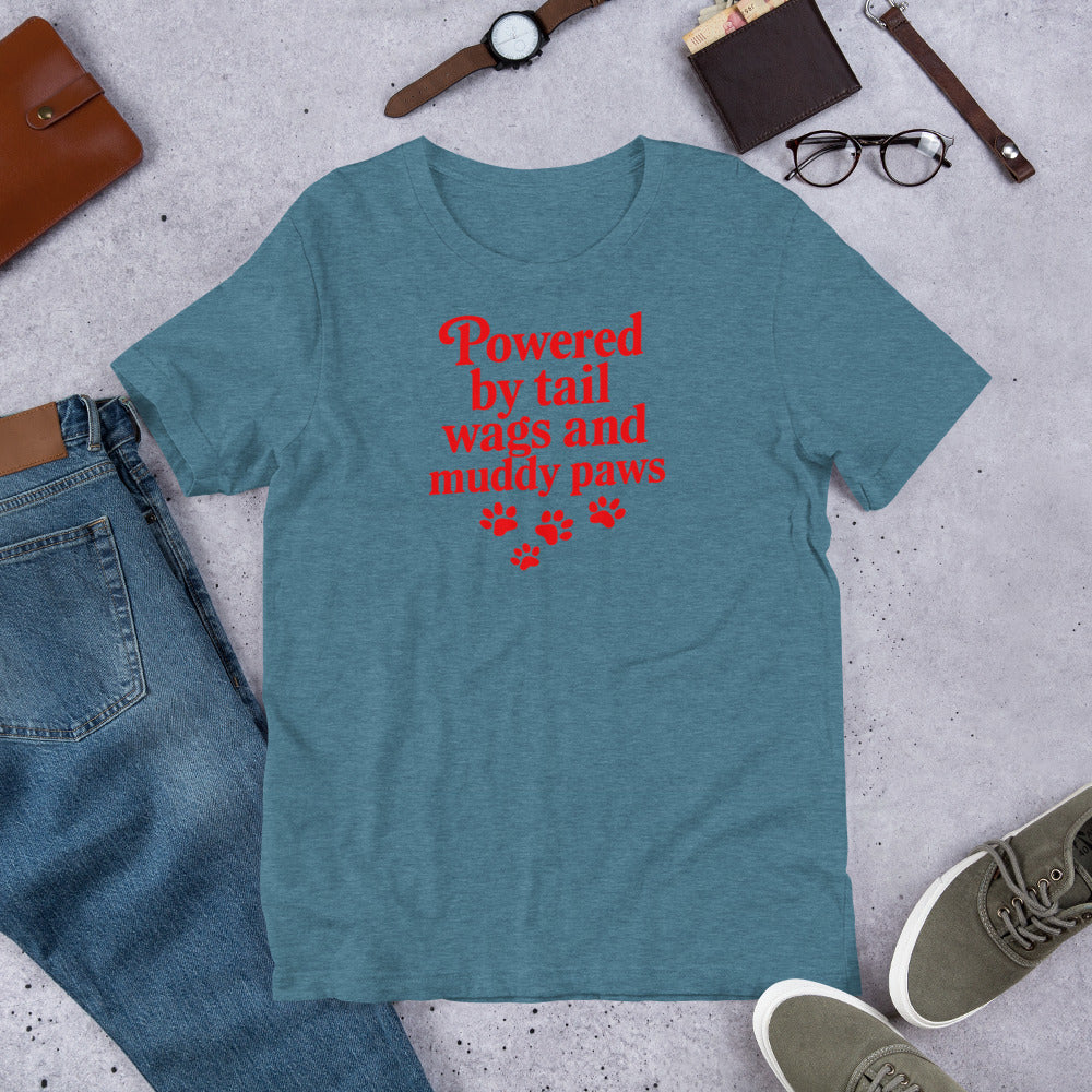 "Powered By Tail Wags And Muddy Paws" - Fun Labrador T-Shirt Blue t-shirt with red text and paw prints on a gray surface with jeans, shoes, and accessories.