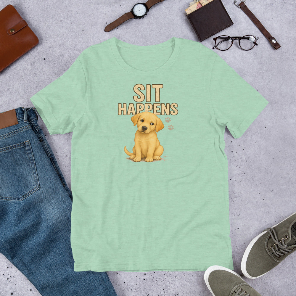 "Sit Happens " – Fun Labrador T-Shirt Mint green t-shirt with a puppy graphic and 'SIT HAPPENS' text on a gray surface with casual items.