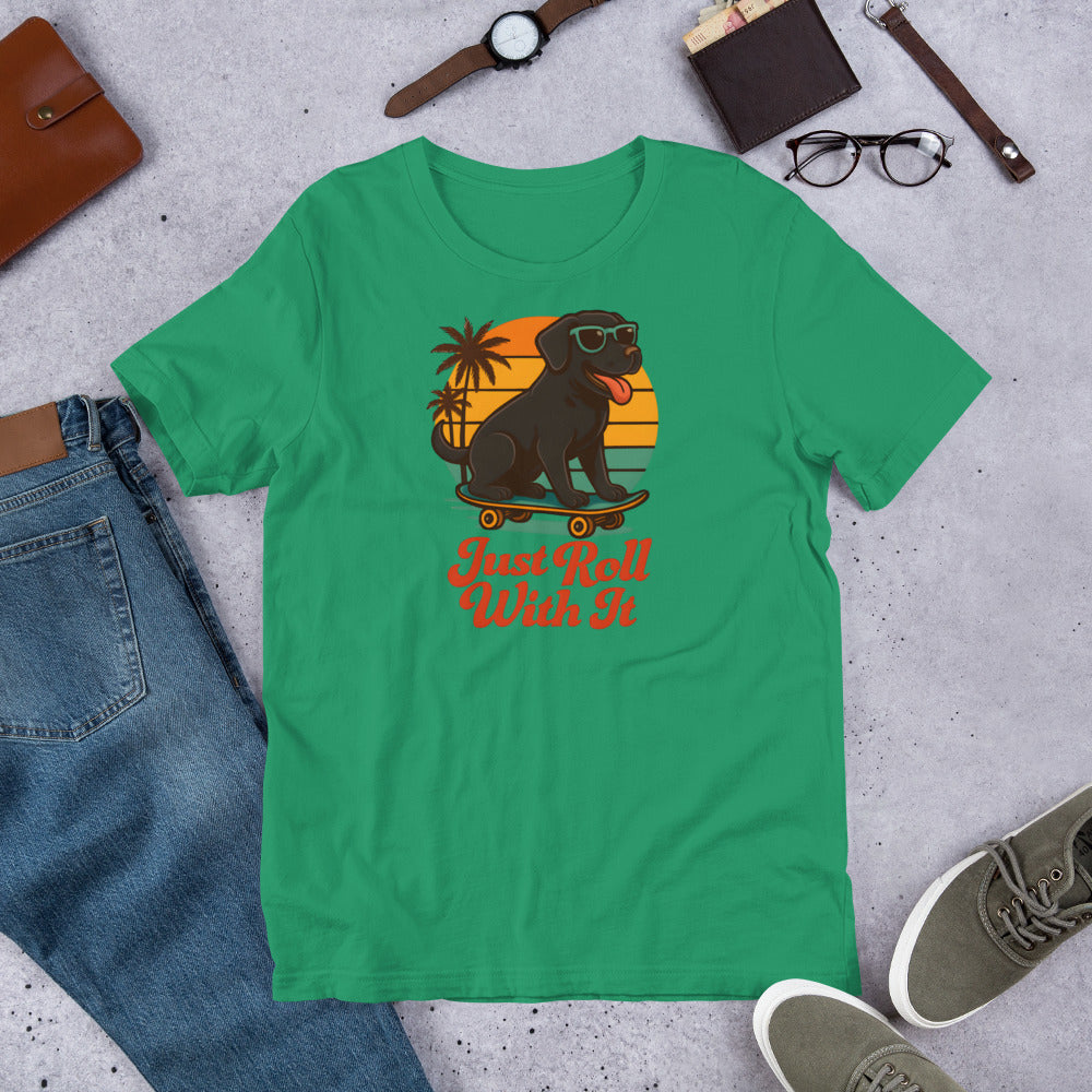 "Just Roll With It" - Black Labrador – Fun Labrador T-Shirt Green t-shirt with a graphic of a dog on a skateboard and text 'Just Roll With It' displayed on a concrete surface with casual items.