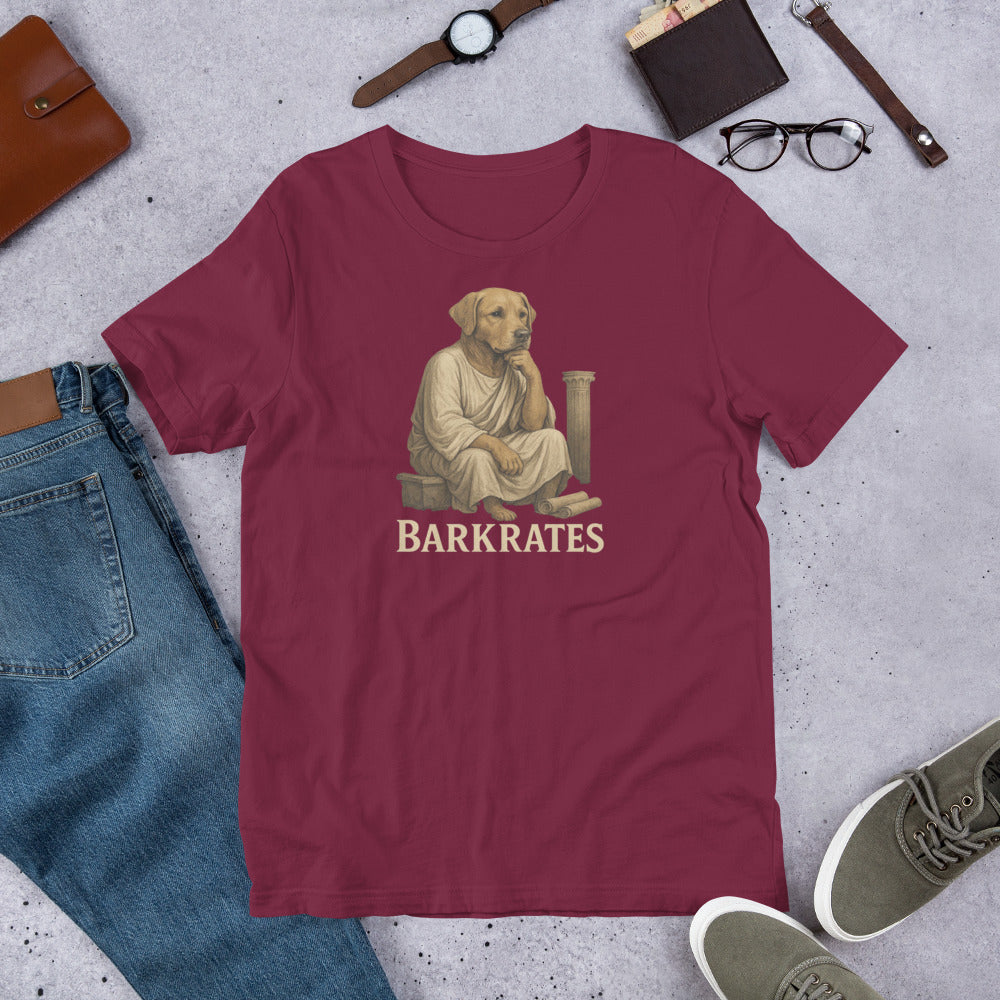 "Barkrates" - Fun Labrador T-Shirt Maroon t-shirt with a graphic of a dog dressed as a Roman senator and 'BARKRATES' text, surrounded by casual items on a concrete surface.