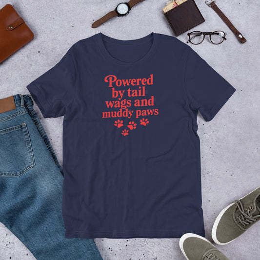 "Powered By Tail Wags And Muddy Paws" - Fun Labrador T-Shirt Navy blue t-shirt with red text and paw prints on a concrete surface with jeans, shoes, and accessories.
