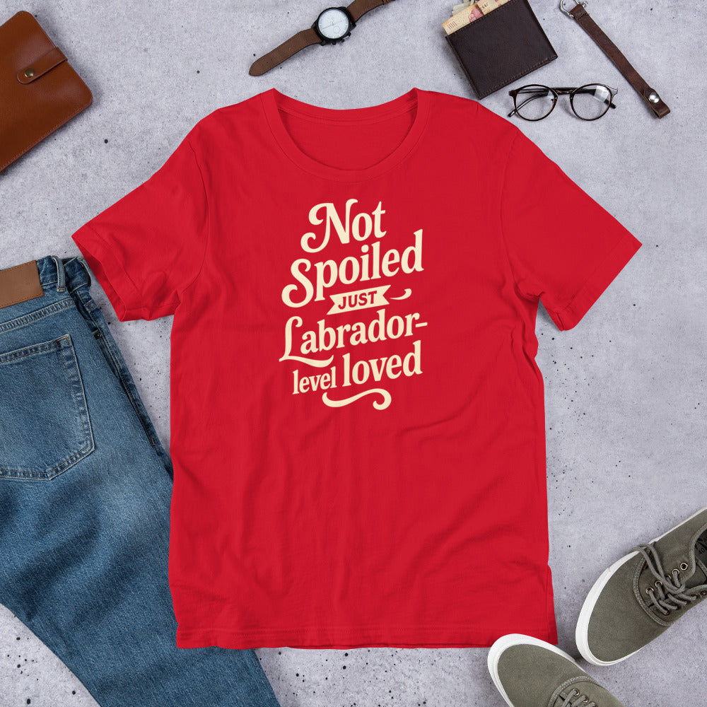 "Not Spoiled Just Labrador Level Loved" - Fun Labrador T-Shirt Red t-shirt with white text on a gray surface with jeans, shoes, and accessories.