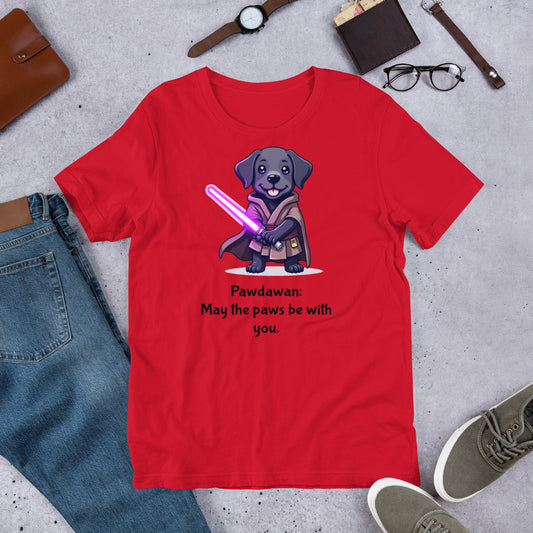 "Pawdawan  " - Fun Labrador T-Shirt Red t-shirt with a dog holding a lightsaber graphic and text on a concrete surface with casual items.