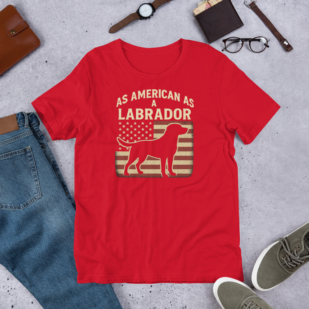 As American As A Labrador - Fun Labrador Tee Red t-shirt with 'As American as a Labrador' graphic on a concrete surface with casual items.
