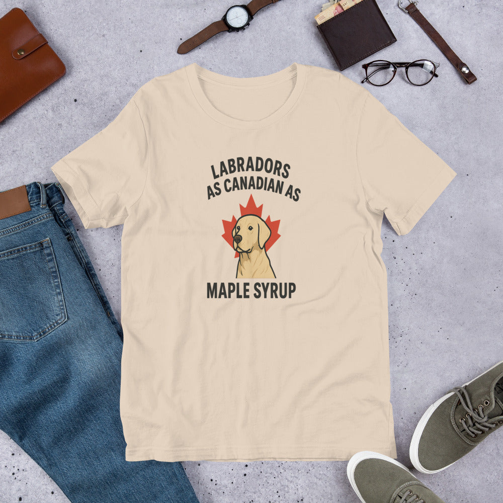 Labradors – As Canadian as Maple Syrup - Fun Labrador Tee Beige t-shirt with Labrador and maple syrup graphic on a gray surface with jeans, shoes, and accessories.