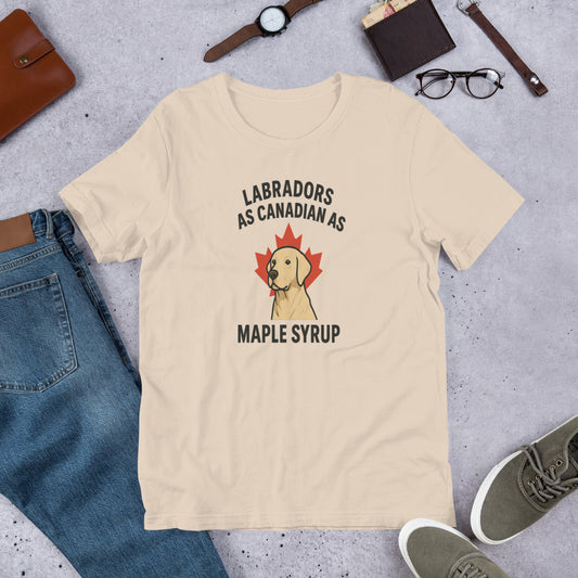 Labradors – As Canadian as Maple Syrup - Fun Labrador Tee Beige t-shirt with Labrador and maple syrup graphic on a gray surface with jeans, shoes, and accessories.