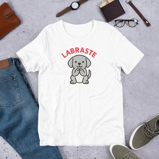 "Labraste Grey Lab" - Fun Labrador  T-Shirt White t-shirt with a dog graphic and 'LABRASTE' text on a gray surface with jeans, shoes, and accessories.